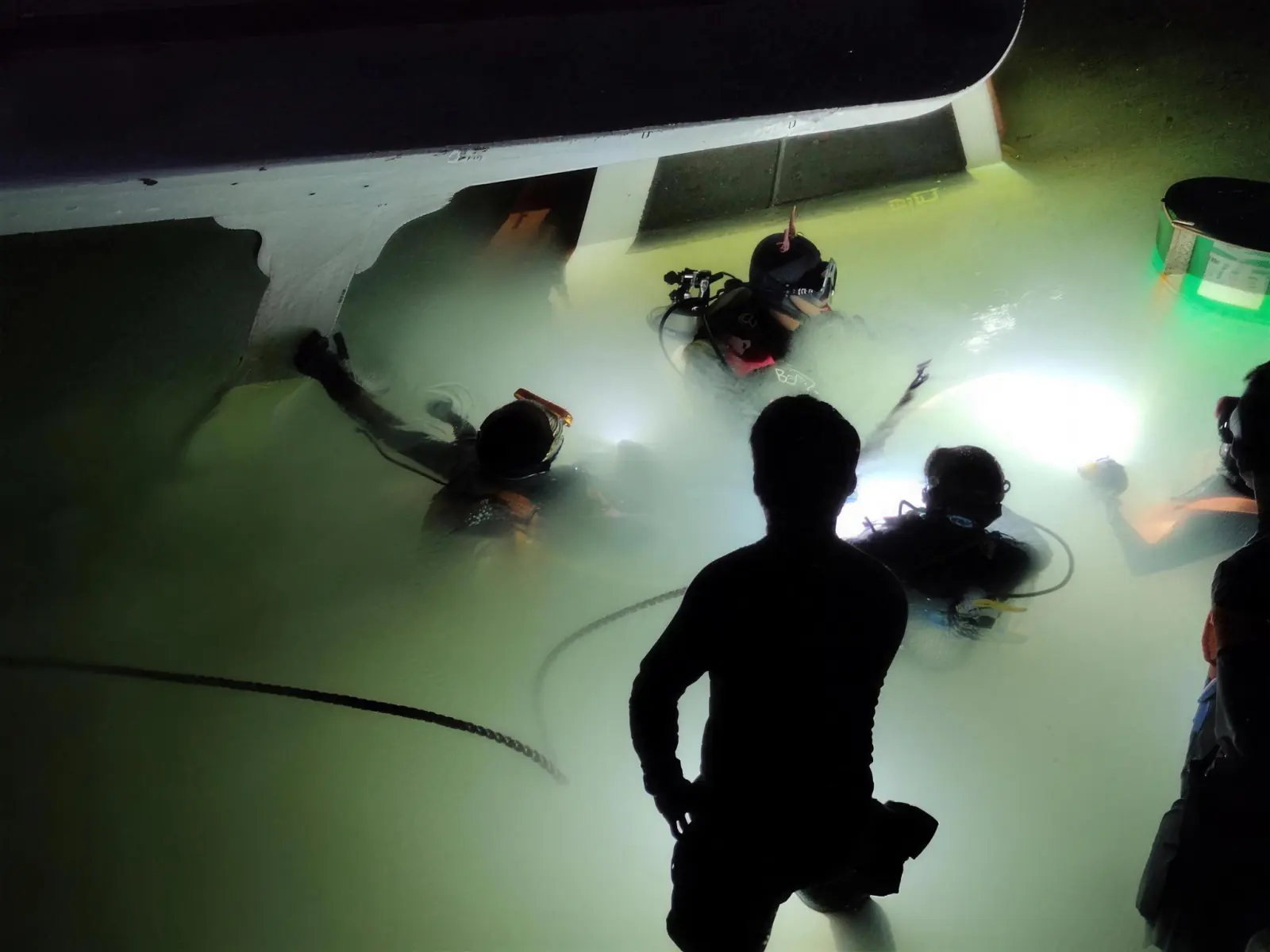 Oceanwide divers inspect a ship's hull at night under floodlights